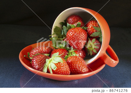 Ripe strawberries in a red plate on the table with a reflection Ripe strawberries in a red plate on the table with a reflection 86741276