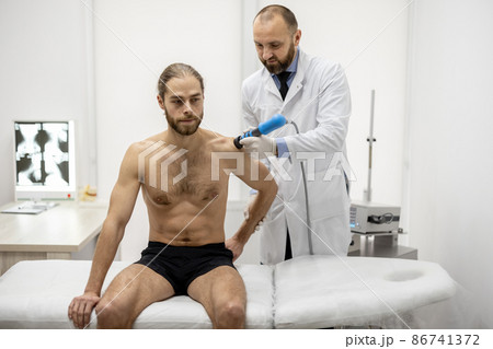 Doctor applies shock wave therapy on men's shoulder Doctor applies shock wave therapy on men's shoulder 86741372