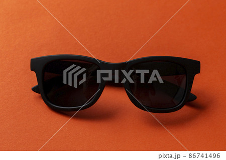 Black sunglasses on orange background, top view, flat lay, minimalistic concept of summer, Black sunglasses on orange background, top view, flat lay, minimalistic concept of summer, 86741496