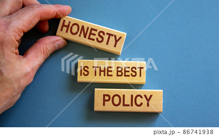 Wooden blocks form the words 'honesty is the best policy' on blue background. Male hand. Wooden blocks form the words 'honesty is the best policy' on blue background. Male hand. 86741938