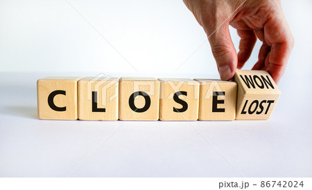 Close won or lost symbol. Businessman turns the wooden cube and changes words Close won to close lost. Beautiful white background, copy space. Business and close won or lost concept. 86742024