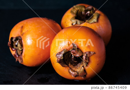Three persimmon Kaki isolated on black background whole 86745409