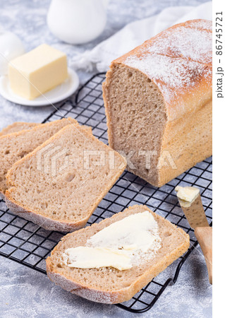 Homemade no knead sandwich bread with butter, on cooling rack, vertical 86745721