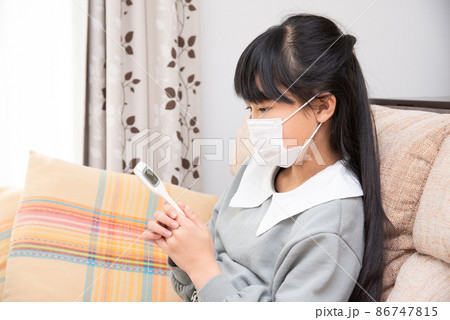 風邪を引いて体温を計る小学生の女の子 風邪を引いて体温を計る小学生の女の子 86747815