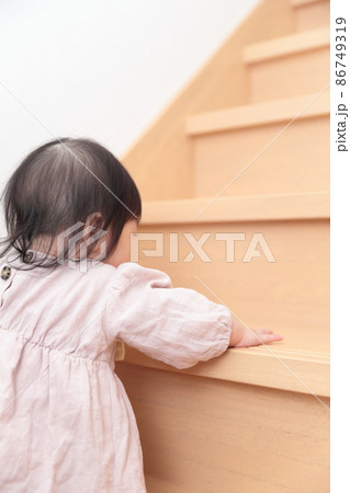 フローリングの階段を登ろうとする0歳の赤ちゃんの女の子 86749319