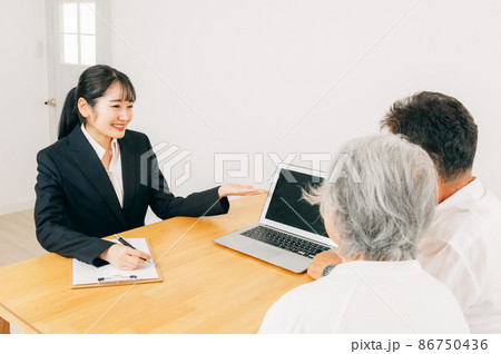 パソコンで説明するスーツ姿の女性と高齢者夫婦 86750436