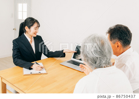 パソコンで説明するスーツ姿の女性と高齢者夫婦 86750437
