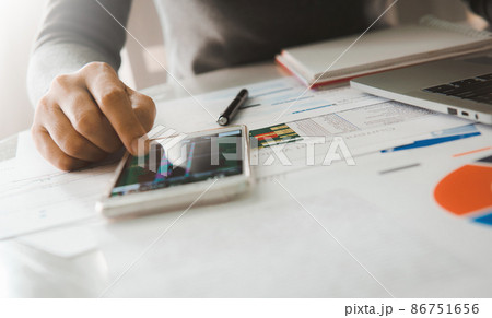Businesswoman analyze business report graph and finance chart using smartphone and computer laptop at corporate office. Businesswoman analyze business report graph and finance chart using smartphone and computer laptop at corporate office. 86751656