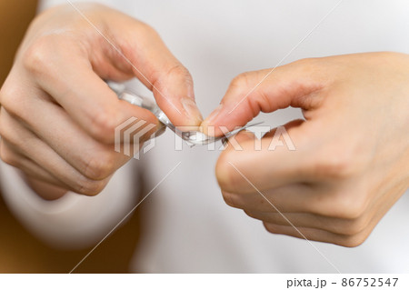 錠剤のPTP包装パッケージを開けるスーツの女性　パーツカット 86752547