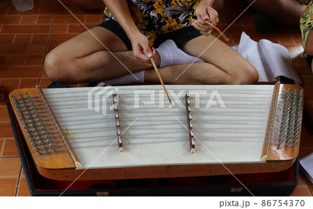Teen age playing Thai dulcimer. 86754370