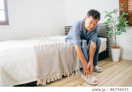 寝室で体調を崩す高齢者男性（足首） 86756035