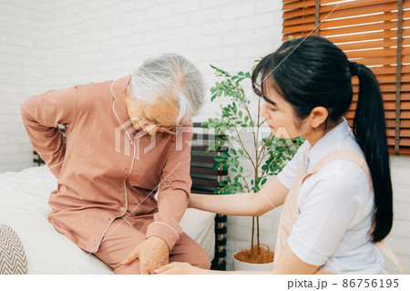 痛がる高齢者女性とエプロン姿の女性(腰痛) 痛がる高齢者女性とエプロン姿の女性(腰痛) 86756195