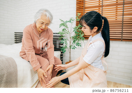 痛がる高齢者女性とエプロン姿の女性(足首) 痛がる高齢者女性とエプロン姿の女性(足首) 86756211