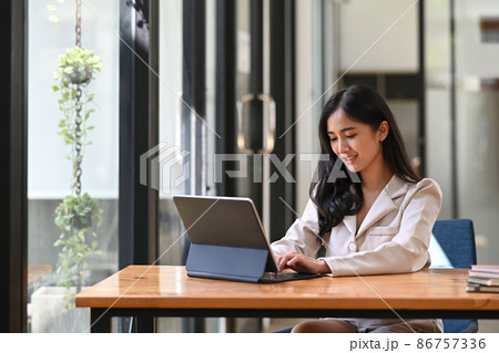 Asian businesswoman using computer tablet while sitting in modern office. 86757336