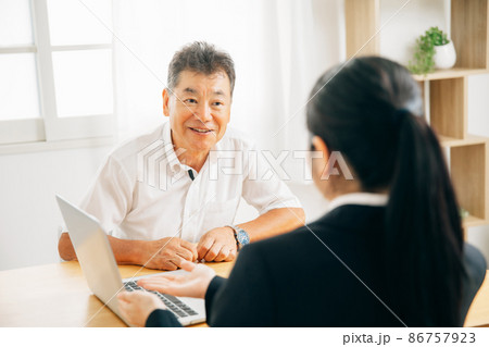 打ち合わせするスーツ姿の女性と高齢者男性 86757923