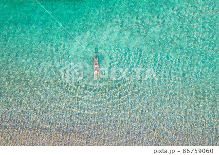 Top, aerial view. Young beautiful woman in a hat and white bikini swimming in sea water on the sand beach. Drone, copter photo. Summer vacation. View from above. Top, aerial view. Young beautiful woman in a hat and white bikini swimming in sea water on the sand beach. Drone, copter photo. Summer vacation. View from above. 86759060