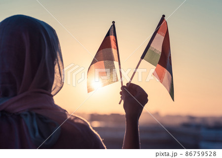 Muslim woman in scarf with Iranian and Germany flags of at sunset.Concept Muslim woman in scarf with Iranian and Germany flags of at sunset.Concept 86759528