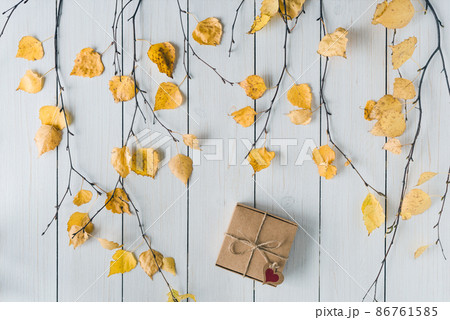 packing gift in a box of kraft paper on white retro wood boards. leaves, birch branches. Thanksgiving. Autumn, fall concept. Flat lay, top view. 86761585