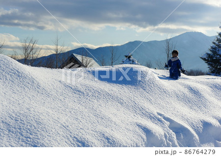 青空の下の雪山で遊ぶ男の子 青空の下の雪山で遊ぶ男の子 86764279