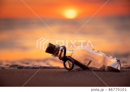 Message in the bottle against the Sun setting down 86770101