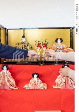 お雛様の飾り付けをしている若い夫婦 お雛様の飾り付けをしている若い夫婦 86771684