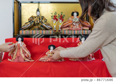 お雛様の飾り付けをしている若い夫婦 86771686