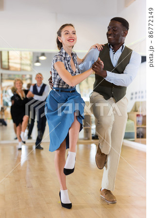 Woman with african man practising charleston dancing Woman with african man practising charleston dancing 86772149