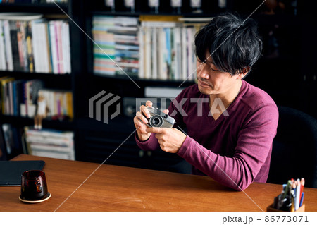 書斎で趣味のカメラをいじる男性 86773071