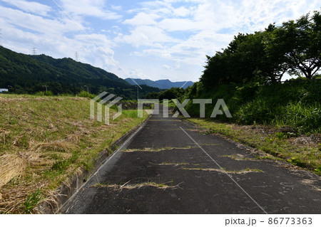 夏の日のまっすぐの荒れた道が伸びていく風景 86773363