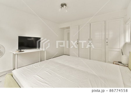 Large double bed in the center of the room with a white duvet cover in a small room 86774558