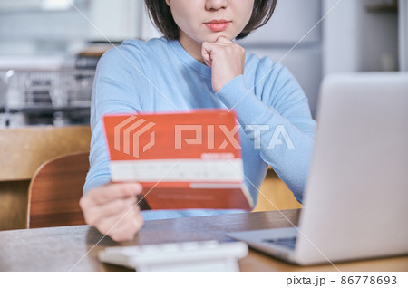 預金通帳を見つめて考える若い女性 86778693