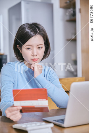 預金通帳を見つめて考える若い女性 86778696