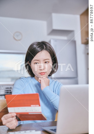 預金通帳を見つめて考える若い女性 預金通帳を見つめて考える若い女性 86778697