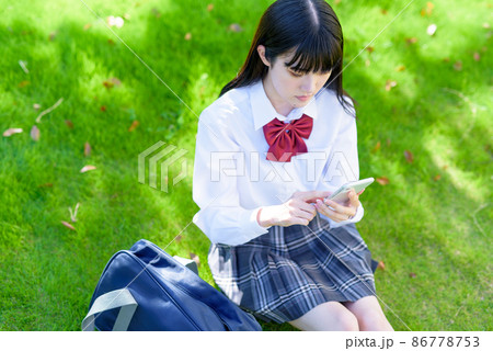 綺麗な新緑の公園の芝生でスマホを使う女子高校生 アプリ SNS 携帯電話 見下ろし構図 俯瞰 綺麗な新緑の公園の芝生でスマホを使う女子高校生 アプリ SNS 携帯電話 見下ろし構図 俯瞰 86778753