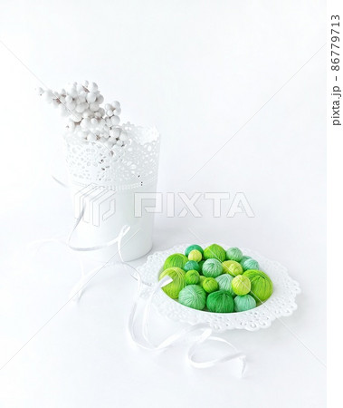 Green threads in a white basket on a white background. Green threads in a white basket on a white background. 86779713