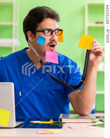 Young doctor sitting in hospital with many conflicting prioritie 86782094