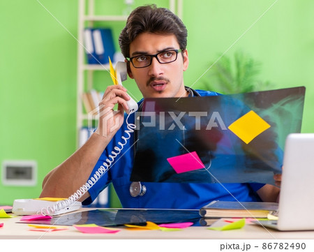 Young doctor sitting in hospital with many conflicting prioritie Young doctor sitting in hospital with many conflicting prioritie 86782490