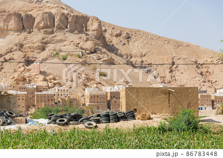 【イエメン】ハドラマウト、岩山の麓に立ち並ぶ石造りの住居と積み上げられた廃タイヤの山 86783448