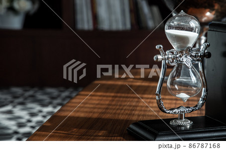 Hourglass on desk with the background of bookshelves in library. 86787168