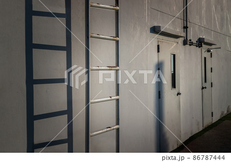 White metal fire escape attached and Two doors to a wall and leading to the roof of a building. 86787444