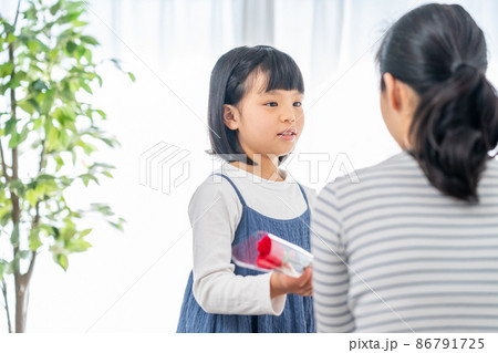 母の日にカーネーションを母親に渡す女の子 母の日にカーネーションを母親に渡す女の子 86791725