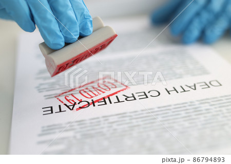 Pathologist putting red covid19 stamp on death certificate closeup Pathologist putting red covid19 stamp on death certificate closeup 86794893