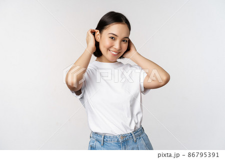 Portrait of cute, beautiful asian woman touching her new short haircut, showing hairstyle, smiling happy at camera, standing over white background Portrait of cute, beautiful asian woman touching her new short haircut, showing hairstyle, smiling happy at camera, standing over white background 86795391