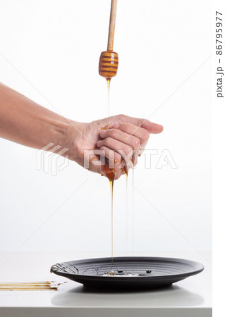 Stick spilling honey on hand on white background. Stick spilling honey on hand on white background. 86795977