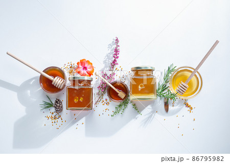 Composition of honey  jars with honey sticks ,flowers and bee pollen on white background 86795982