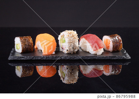 Assorted sushi served on slate plate on dark background. Japanese food. Assorted sushi served on slate plate on dark background. Japanese food. 86795988