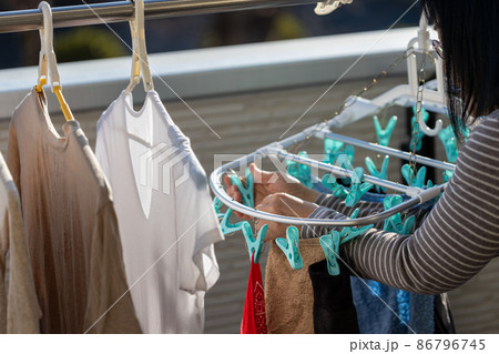 ベランダで女性が洗濯物を干しているところ 86796745