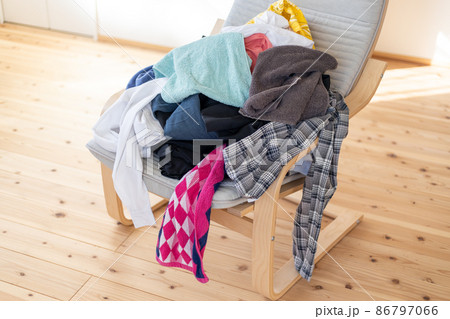 椅子の上に置いてある、取り入れた洗濯物の山 86797066
