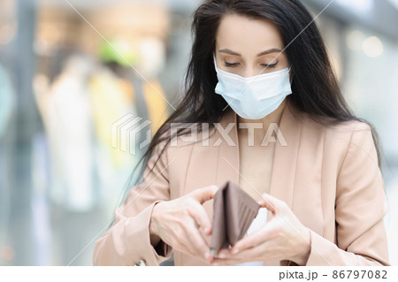 Woman in face mask look in wallet, female being short of money Woman in face mask look in wallet, female being short of money 86797082