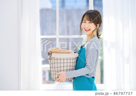 家事をする洗濯カゴを持ったエプロン姿の若い主婦 家事をする洗濯カゴを持ったエプロン姿の若い主婦 86797737